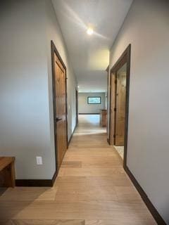 hall with baseboards and light wood-style floors