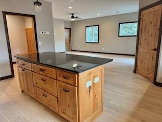 kitchen featuring light wood-style flooring, dark countertops, recessed lighting, a ceiling fan, and a kitchen island