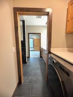 laundry area with baseboards, cabinet space, washer / clothes dryer, and stone finish flooring