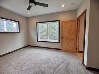 spare room with baseboards, light colored carpet, ceiling fan, and plenty of natural light