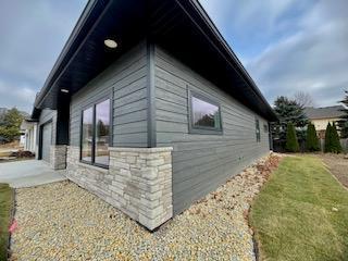 view of side of property with stone siding and a yard