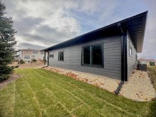 view of side of property with a lawn and cooling unit