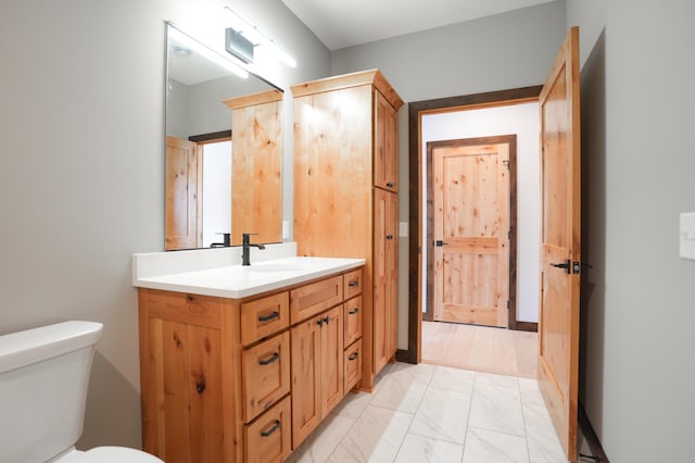 half bath featuring marble finish floor, toilet, and vanity