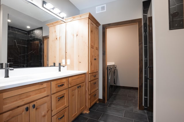 full bathroom featuring visible vents, independent washer and dryer, tiled shower, a sink, and tile patterned flooring