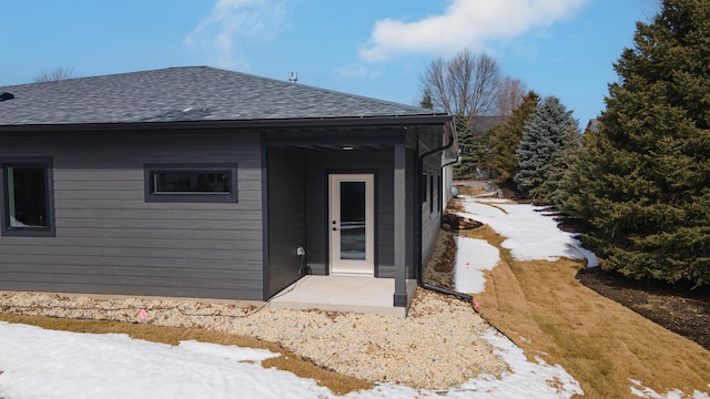 view of exterior entry with roof with shingles