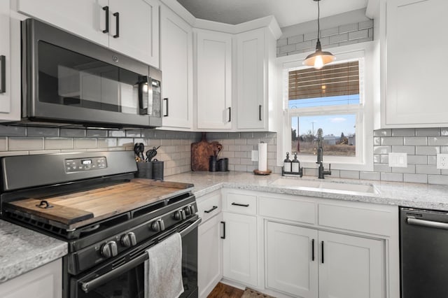 kitchen with sink, dishwasher, light stone counters, gas stove, and white cabinets