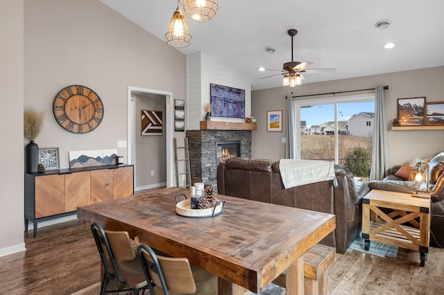 dining area with vaulted ceiling, ceiling fan, a fireplace, and dark hardwood / wood-style flooring