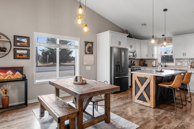 kitchen featuring a kitchen island, appliances with stainless steel finishes, pendant lighting, and white cabinets