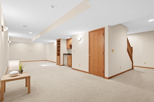 finished below grade area with stairs, bar area, light colored carpet, baseboards, and recessed lighting