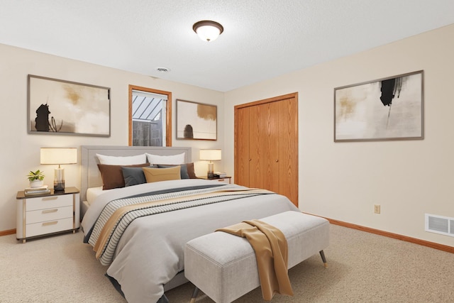 carpeted bedroom with baseboards, visible vents, a textured ceiling, and a closet