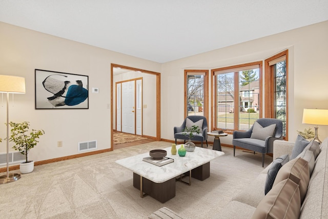 living room with visible vents, baseboards, and light colored carpet