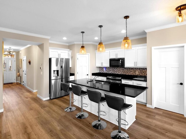 kitchen with white cabinets, stainless steel fridge, sink, and an island with sink