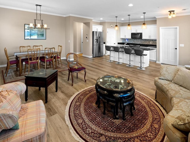 living room featuring ornamental molding, light hardwood / wood-style floors, and a notable chandelier