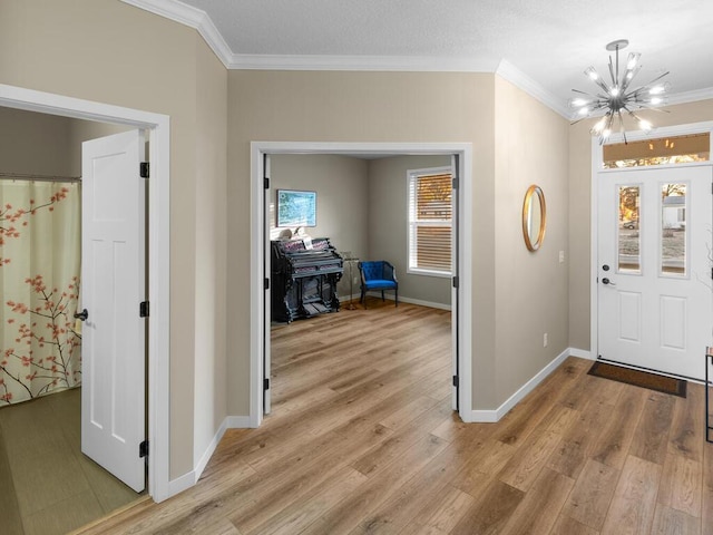 foyer with light hardwood / wood-style flooring, ornamental molding, and a notable chandelier