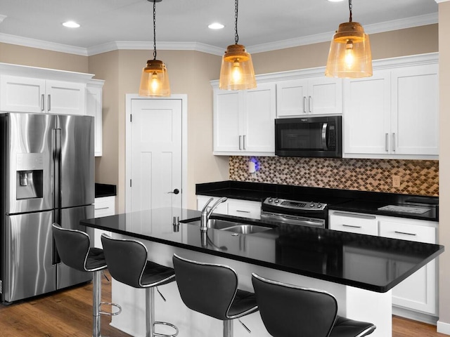 kitchen featuring sink, hanging light fixtures, appliances with stainless steel finishes, an island with sink, and white cabinets