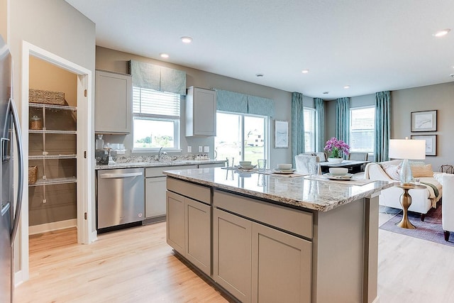 kitchen with gray cabinetry, a center island, stainless steel appliances, and light hardwood / wood-style floors