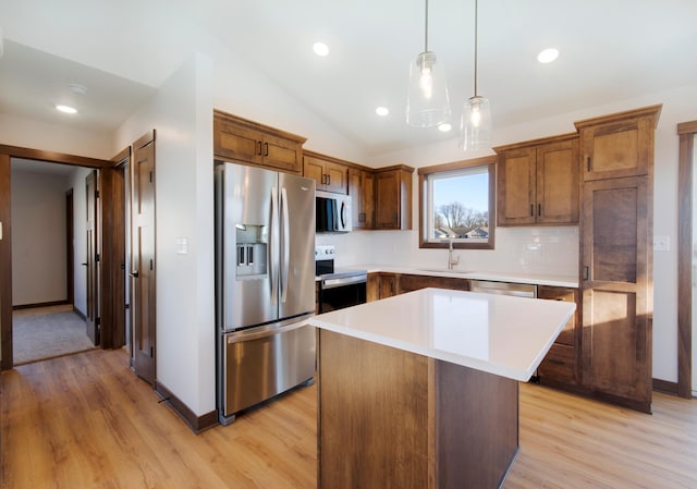 kitchen featuring sink, light wood-type flooring, a kitchen island, pendant lighting, and stainless steel appliances