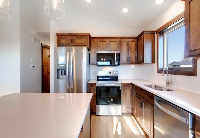 kitchen featuring appliances with stainless steel finishes, vaulted ceiling, a sink, and backsplash