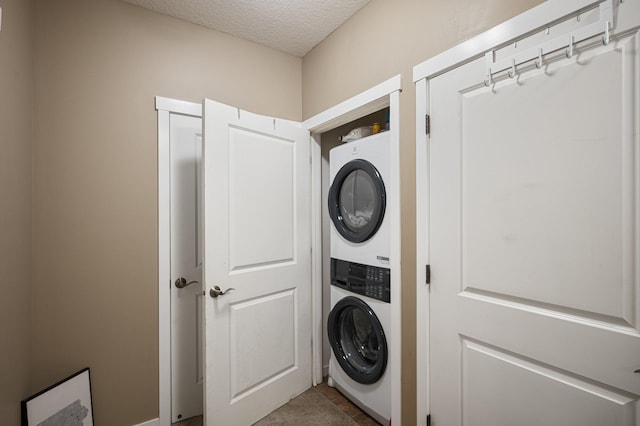 washroom with tile patterned flooring, a textured ceiling, and stacked washer / dryer