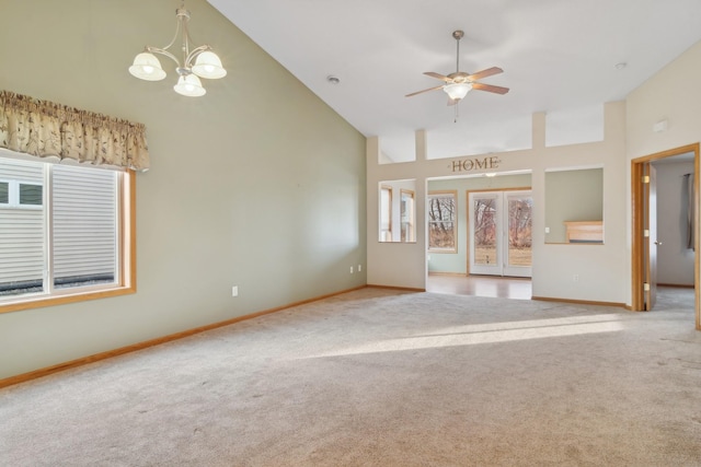 unfurnished living room with ceiling fan with notable chandelier, carpet floors, and high vaulted ceiling