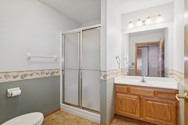 bathroom with vanity, toilet, an enclosed shower, and a textured ceiling