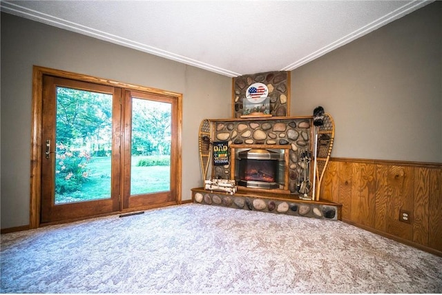 living room with wood walls, a fireplace, carpet, and crown molding