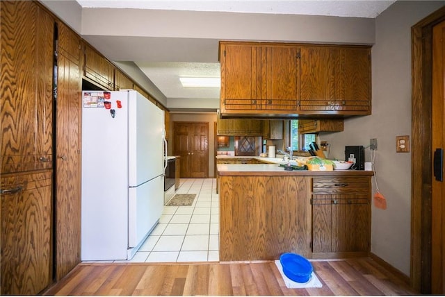 kitchen featuring kitchen peninsula, electric range oven, white fridge, and sink