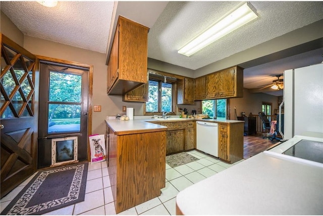 kitchen with ceiling fan, kitchen peninsula, a textured ceiling, white appliances, and light tile patterned floors