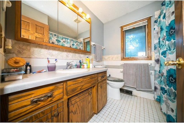 bathroom featuring vanity, a textured ceiling, tile walls, tile patterned flooring, and toilet