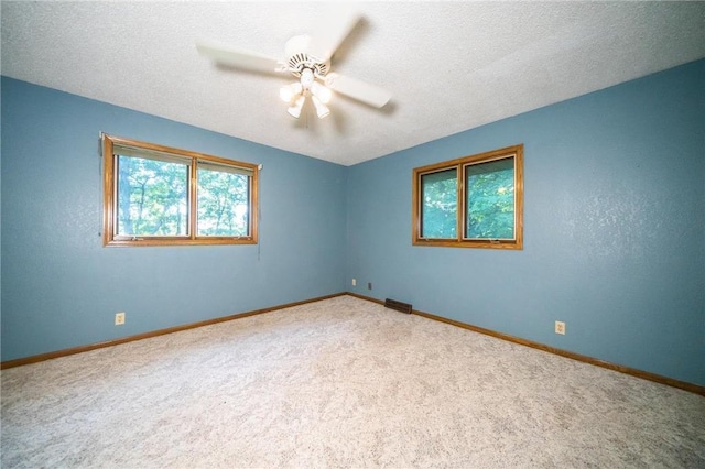 carpeted empty room featuring ceiling fan and a textured ceiling