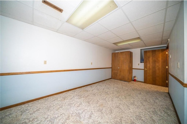 carpeted empty room featuring a drop ceiling