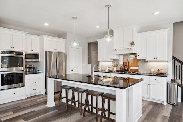 kitchen featuring white cabinetry, sink, decorative light fixtures, a center island with sink, and appliances with stainless steel finishes