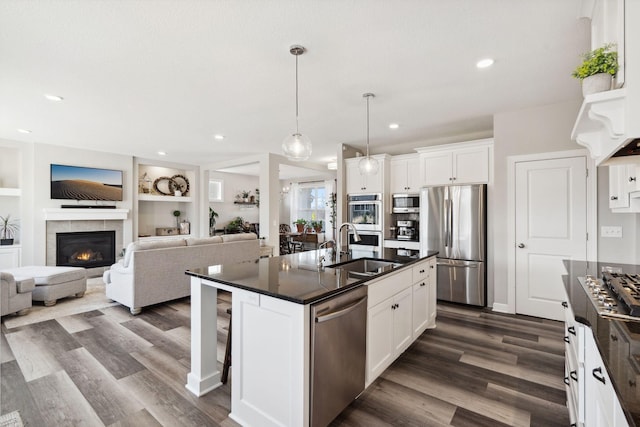 kitchen with white cabinets, stainless steel appliances, built in features, and a kitchen island with sink