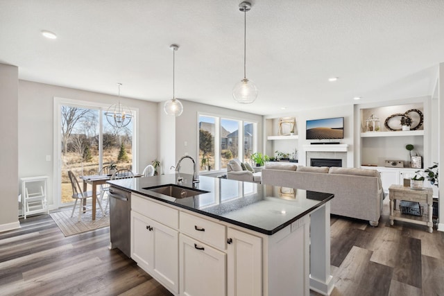 kitchen featuring dishwasher, a center island with sink, sink, decorative light fixtures, and white cabinetry