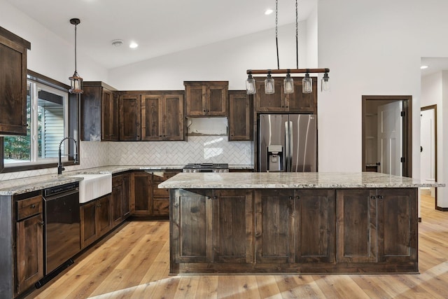 kitchen featuring a center island, decorative light fixtures, stainless steel fridge, and sink