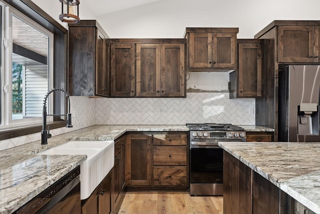 kitchen featuring light stone countertops, sink, stainless steel appliances, backsplash, and lofted ceiling