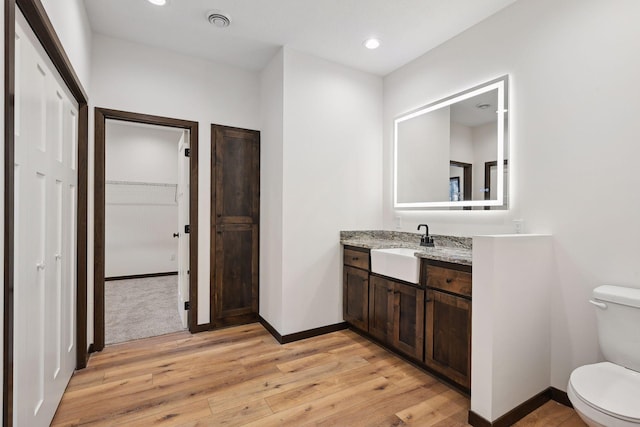 bathroom featuring wood-type flooring, vanity, and toilet