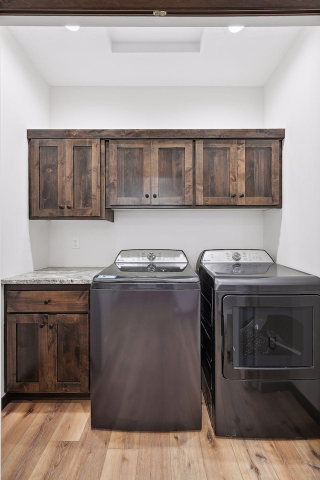 washroom with cabinets, light hardwood / wood-style flooring, and washing machine and clothes dryer