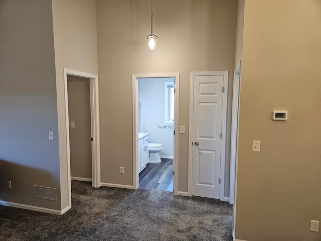 hall featuring dark colored carpet and a high ceiling