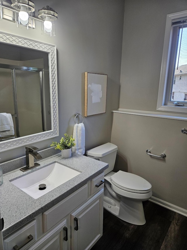 bathroom featuring wood-type flooring, vanity, toilet, and a shower with door