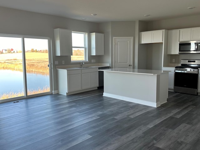 kitchen featuring sink, a center island, dark hardwood / wood-style floors, white cabinets, and appliances with stainless steel finishes