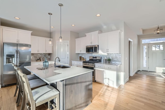 kitchen featuring hanging light fixtures, appliances with stainless steel finishes, sink, and white cabinets