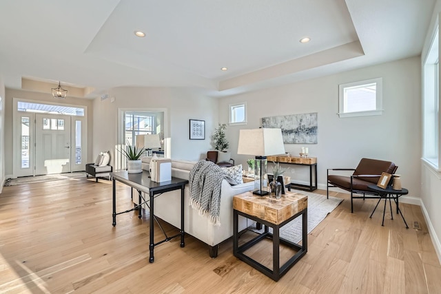 living room with plenty of natural light, light hardwood / wood-style flooring, and a tray ceiling