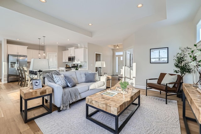 living room featuring a tray ceiling and light hardwood / wood-style floors