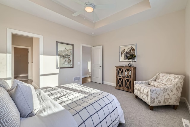 carpeted bedroom featuring a tray ceiling and ceiling fan