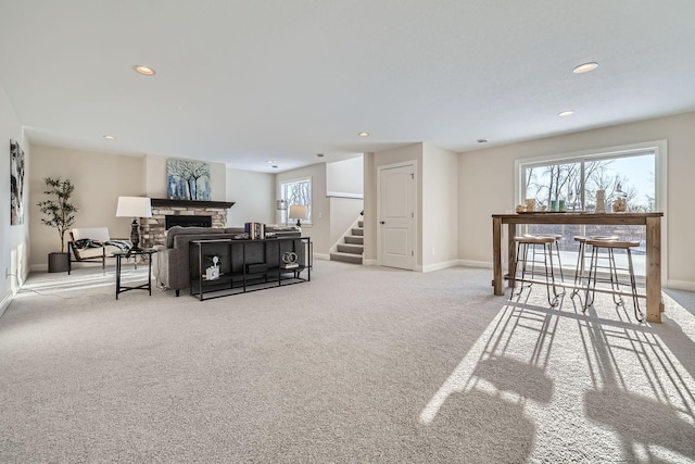 carpeted living room with a stone fireplace