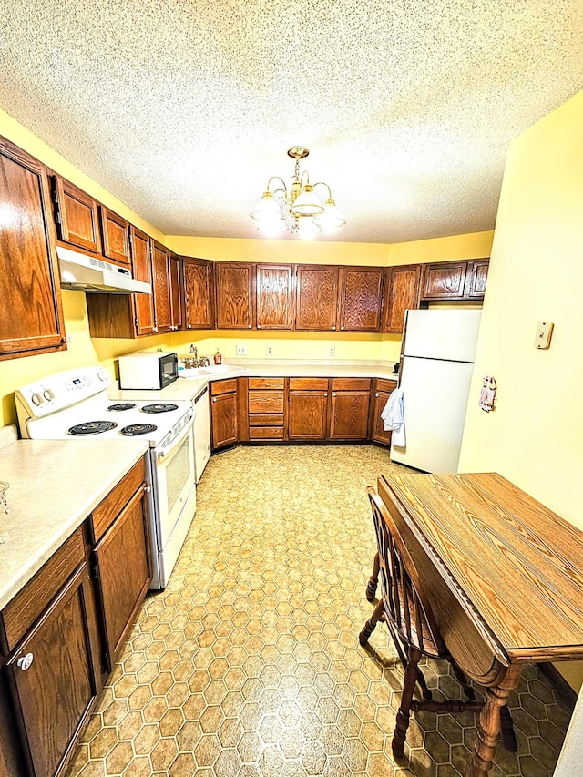 kitchen with white appliances, a notable chandelier, and a textured ceiling