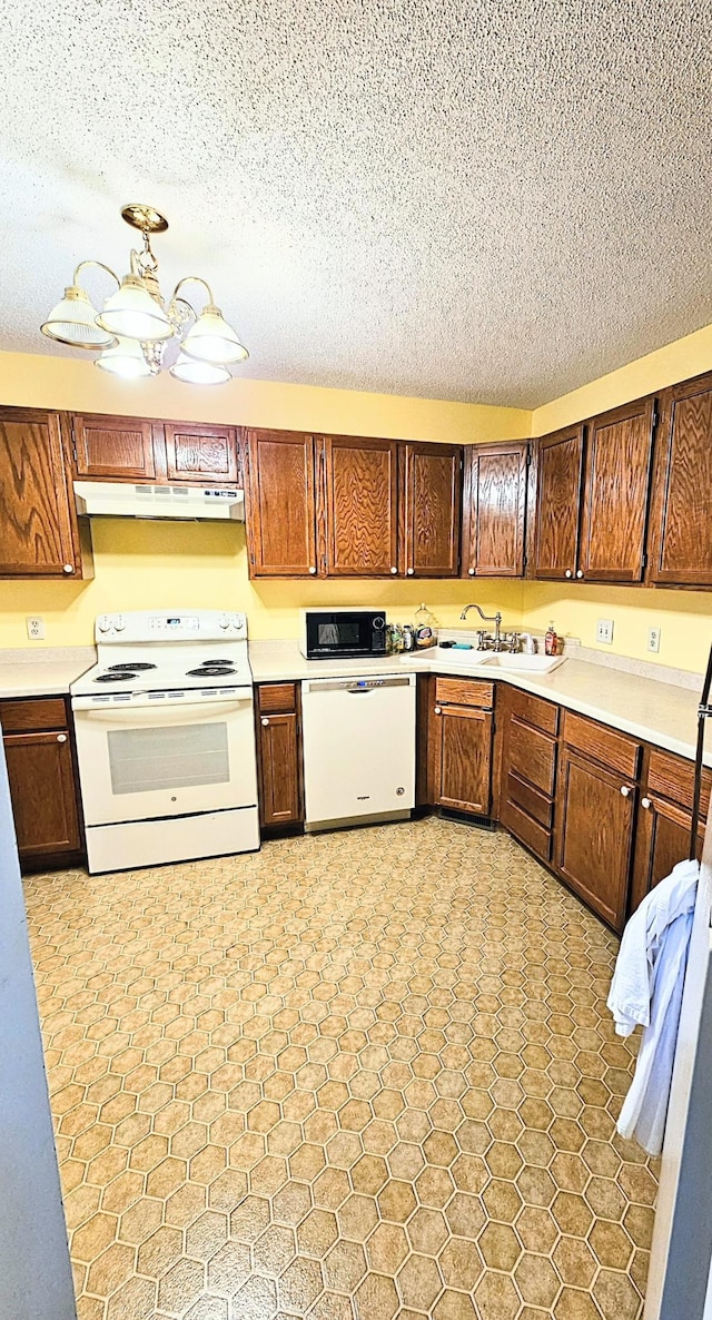 kitchen featuring white appliances, a textured ceiling, and sink