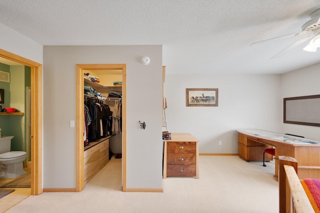 carpeted bedroom with ensuite bathroom, ceiling fan, a spacious closet, a textured ceiling, and a closet