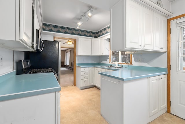 kitchen featuring stainless steel appliances, light colored carpet, ceiling fan, sink, and white cabinets